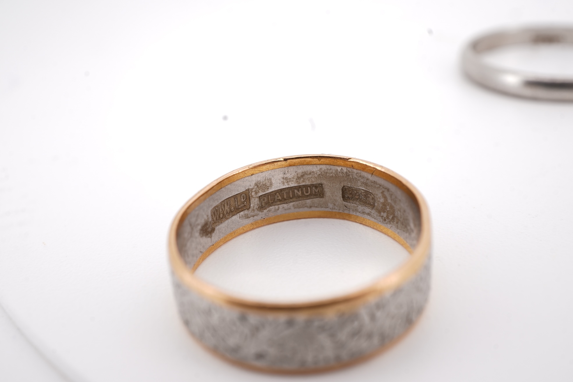 Three rings, comprising: a platinum wedding band, size N1/2, stamped PLAT, gross weight 3 grams; a bicoloured band, size J, stamped PLATINUM 22CT, gross weight 3 grams; and a ring set with a diamond weighing approximatel